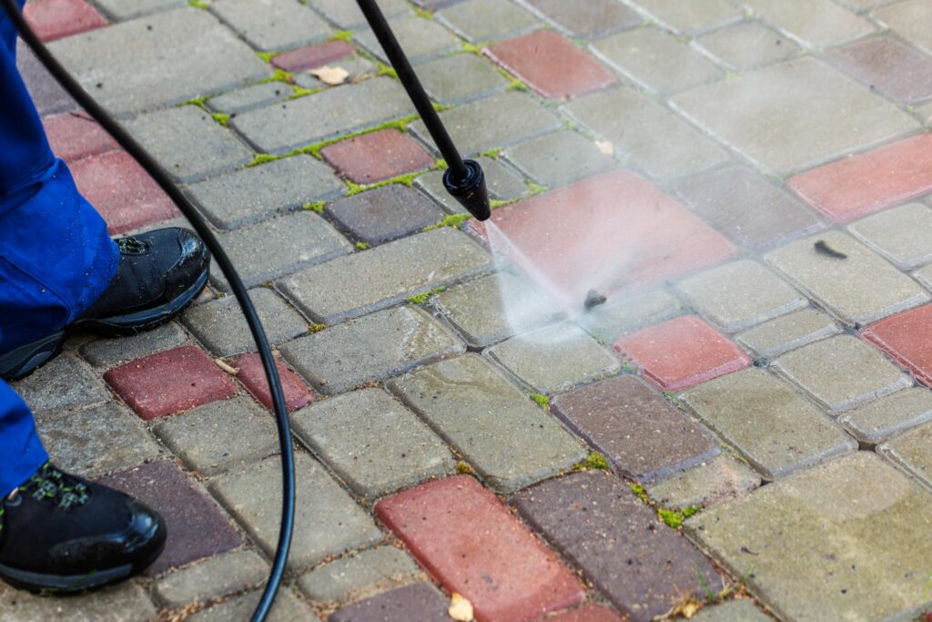 a person using a pressure washer on a brick sidewalk